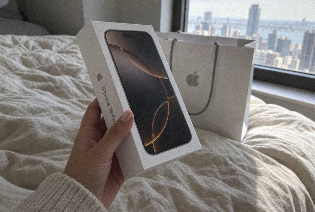 Un iPhone dans sa boîte ouverte sur un drap crème